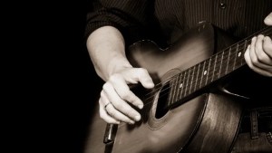 black and white photograph showing close up of hands playing blues guitar