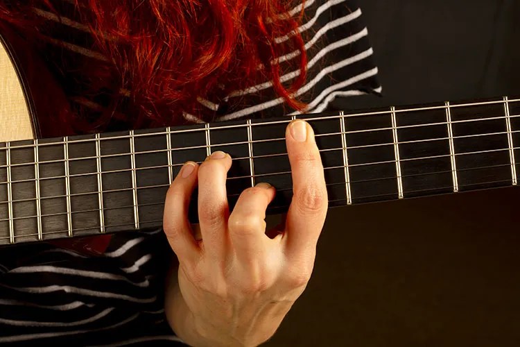 Gretchen Menn plays an acoustic guitar