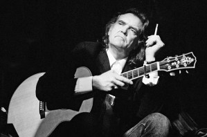 Guy Clark seated with acoustic guitar