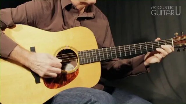 Close up photograph of man playing an acoustic guitar, demonstrating a harmonized major from the lesson video