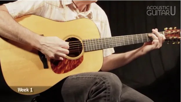 close up photograph of scott nygaards hands demonstrating open strings on an acoustic guitar