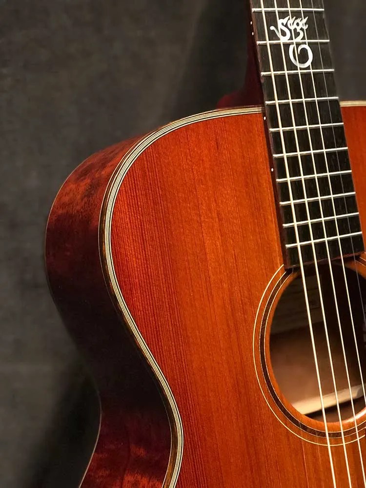 Closeup of binding, strings, and soundhole of a 2021 Santa Cruz OM Custom acoustic guitar made from Tunnel 13 Redwood