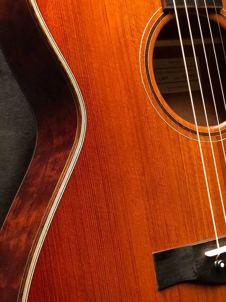 Closeup of binding, soundhole, and bridge of a 2021 Santa Cruz OM Custom acoustic guitar made from Tunnel 13 Redwood