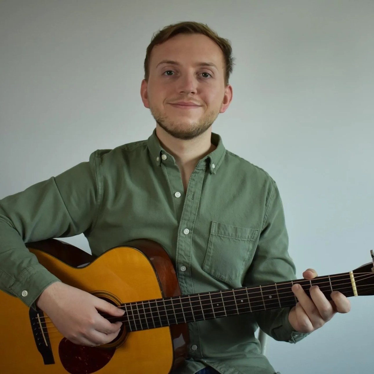 Luke Edwards headshot with a guitar